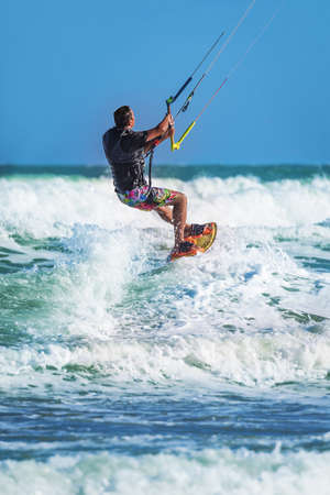 Athletic man riding on kite surf board on a sea wavesの写真素材