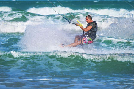 Athletic man riding on kite surf board on a sea wavesの写真素材