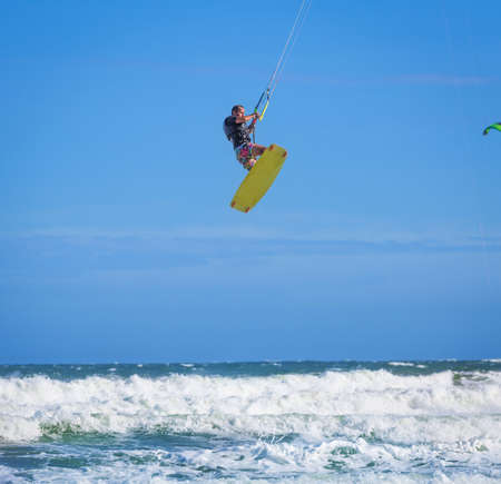Athletic man riding on kite surf board on a sea wavesの写真素材