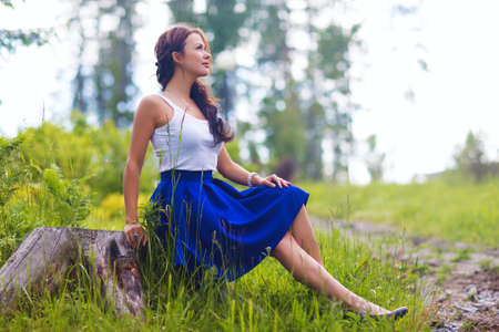 Young pretty woman poses showing dress summer outdoors in sunset lightの写真素材