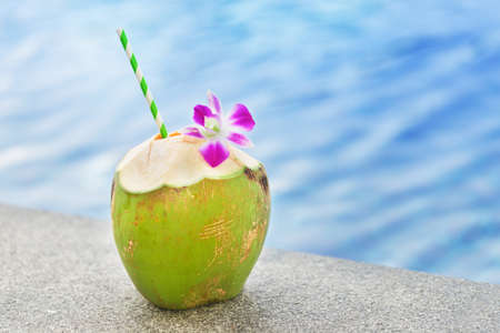 Fresh coconut drink with orchid flower near swimming poolの写真素材