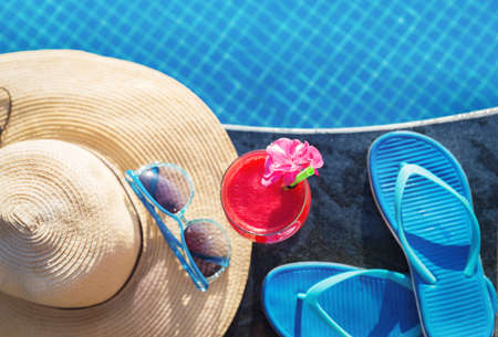 Water melon red fresh juice smoothie drink cocktail slippers, straw hat and sunglasses near swimming poolの写真素材
