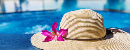Straw hat with orchid flower near swimming pool - holiday conceptの写真素材