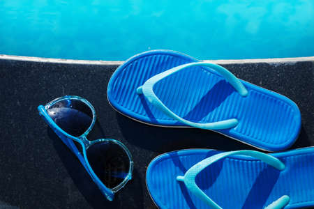 Blue slippers and sun glasses near swimming pool - holiday conceptの写真素材