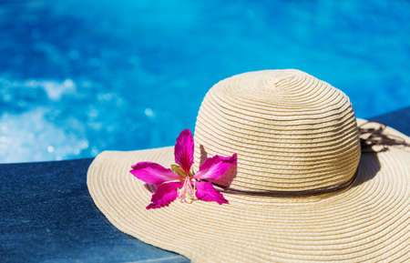 Straw hat with orchid flower near swimming pool - holiday conceptの写真素材