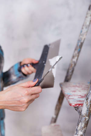 house improvement by woman worker puts finishing layer of stucco on the wall using a plastering...
