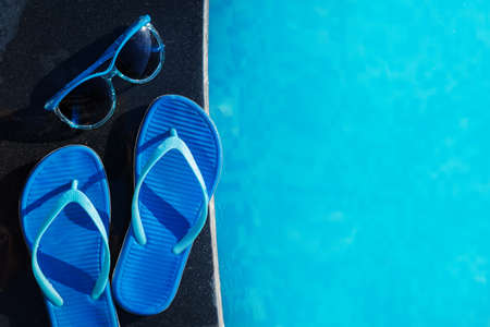 Blue slippers and sun glasses near swimming pool - holiday conceptの写真素材