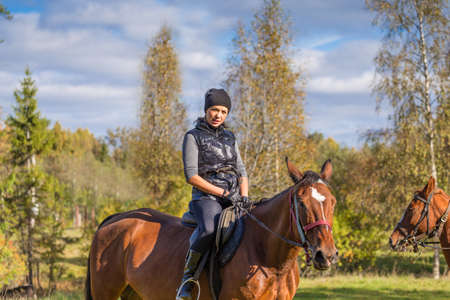 Elegant attractive woman riding a horse farmの写真素材
