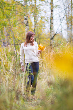 Pretty woman in a yellow autumn parkの写真素材