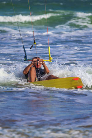 Athletic man riding on kite surf board on a sea waves