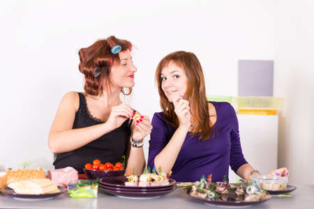Two young pretty woman housewife cooking with curlers on hairの写真素材
