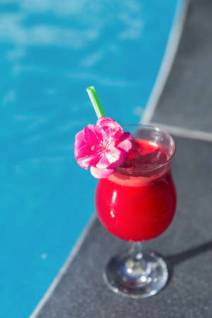 Glass of fresh watermelon smoothie juice drink on border of a swimming pool - holiday tropical conceptの写真素材