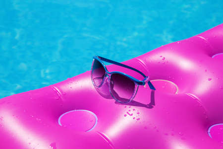 Sunglasses with pink mattress at the swimming pool - holiday tropical conceptの写真素材
