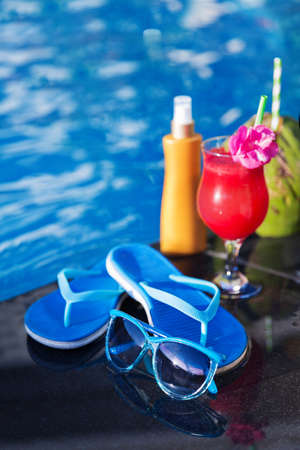 Water-melon  fresh fruit smothie drink with sunglasses, sunscreen creame, slippers and coconut on the swimming pool border - holiday tropical conceptの写真素材