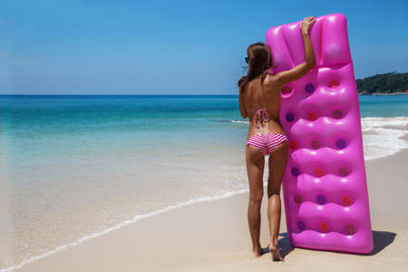 Young slim brunette woman in sunglasses sunbathe with an air mattress on the tropic beachの写真素材