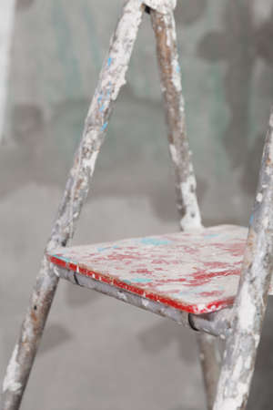 Old painted and stucco ladder on a concrete wall backgroundの写真素材