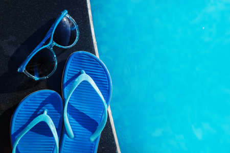 Blue slippers and sunglasses on border of a swimming pool - holiday tropical conceptの写真素材