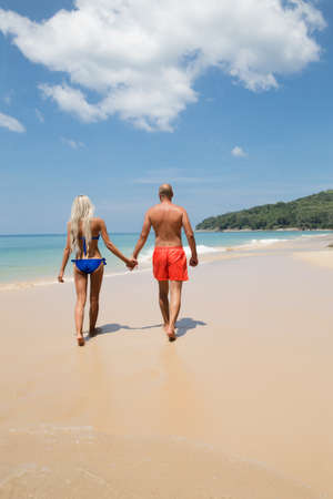 Pretty couple holding hands walking on a summer tropic beachの写真素材