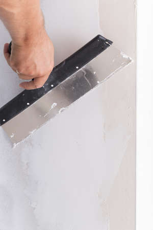 house improvement by worker puts finishing layer of stucco on the wall using a plastering trowelの写真素材