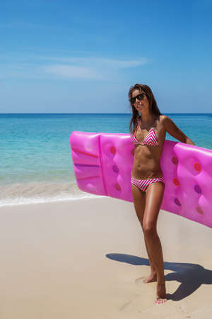 Young slim brunette woman in sunglasses sunbathe with an air mattress on the tropic beachの写真素材