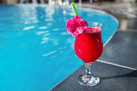 Glass of fresh watermelon smoothie juice drink on border of a swimming pool - holiday tropical conceptの写真素材