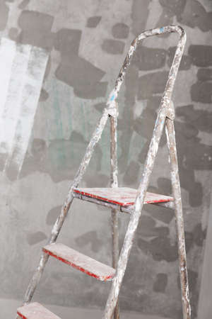 Old painted and stucco ladder on a concrete wall backgroundの写真素材