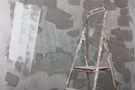 Old painted and stucco ladder on a concrete wall backgroundの写真素材