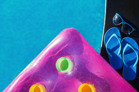 Pink air mattress, slippers and sunglases on border of a swimming pool - holiday tropical conceptの写真素材