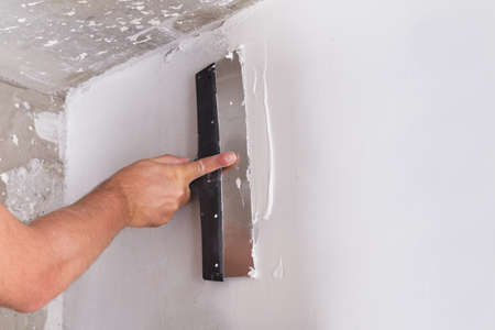 house improvement by worker puts finishing layer of stucco on the wall using a plastering trowelの写真素材