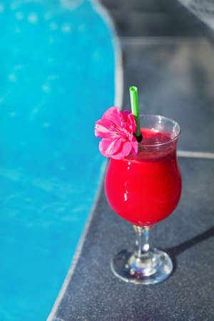 Glass of fresh watermelon smoothie juice drink on border of a swimming pool - holiday tropical conceptの写真素材