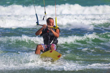 Athletic man riding on kite surf board in a sea wavesの写真素材