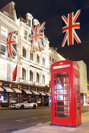 United Kingdom, England, London - 2016 June 17: Popular tourist Red phone booth with flags union jack in night lights illuminationのeditorial素材