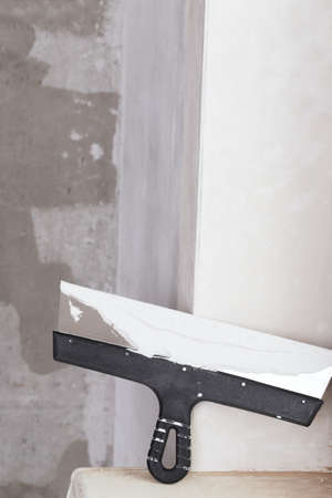 house improvement by worker puts finishing layer of stucco on the wall using a plastering trowelの写真素材