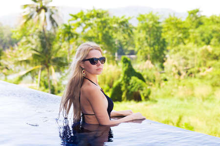 beautiful young slim blonde woman gets suntan near the swimming poolの写真素材
