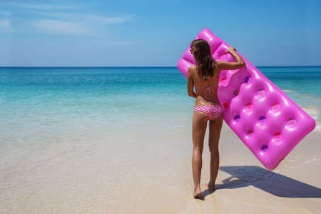 Young slim brunette woman in sunglasses sunbathe with an air mattress on the tropic beachの写真素材