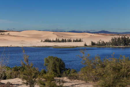 White sand dunes with the lake and trees at the Mui Ne village Vietnamの写真素材