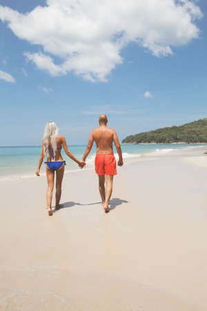 Pretty couple walking on a sunny tropic beachの写真素材