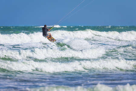 Athletic man riding on kite surf board on a sea wavesの写真素材