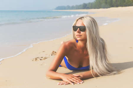 Slim blonde long haired woman in bikini on tropical beachの写真素材