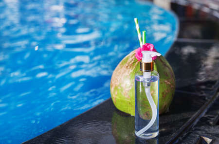 Coconut juice drink with flower and bottle of oil on border of a swimming pool - holiday tropical conceptの写真素材