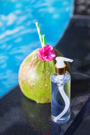 Coconut juice drink with flower and bottle of oil on border of a swimming pool - holiday tropical conceptの写真素材