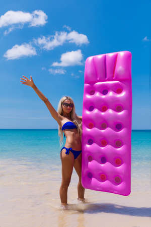 Slim blonde woman with air mattress on a tropic beachの写真素材