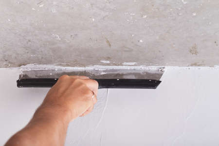 house improvement by worker puts finishing layer of stucco on the wall using a plastering trowelの写真素材