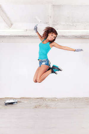 young beautiful woman jump and paints the wall and white paint rollerの写真素材
