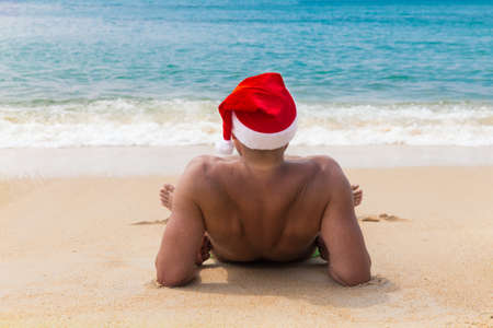 Man in Christmas red hat on a tropic sea beachの写真素材