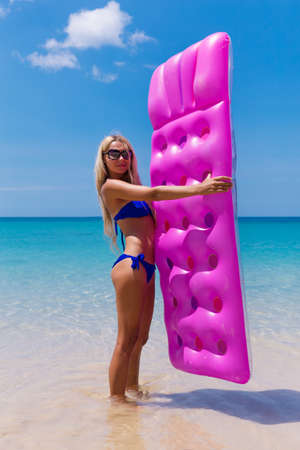 Slim blonde woman with air mattress on a tropic beachの写真素材