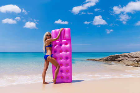 Slim blonde woman with air mattress on a tropic beachの写真素材