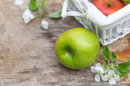 Fresh sweet juicy red and green apples with flowers on a wooden background in gardenの写真素材