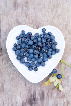 forest blueberries heart plate wooden backgroundの写真素材