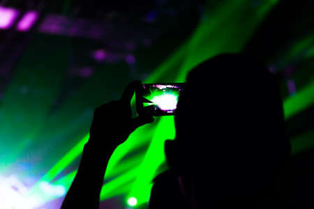 Man taking photo video by mobile phone of silhouettes crowd party concert music happyの写真素材